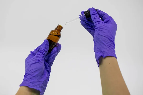 Zárja be az üveg kozmetikai üveg csepegtető a kezében gumikesztyűvel — Stock Fotó