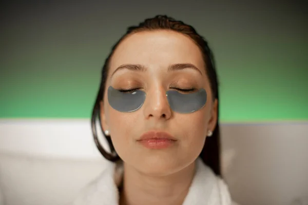 Tutup potret wanita menarik dengan tambalan mata kosmetik santai di spa — Stok Foto