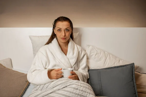 Hermosa chica tranquila relajante en el té de hierbas homedrinking en albornoz blanco — Foto de Stock