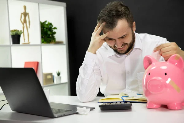 Businessman in panic with broken piggy bank on desk, calculate bills