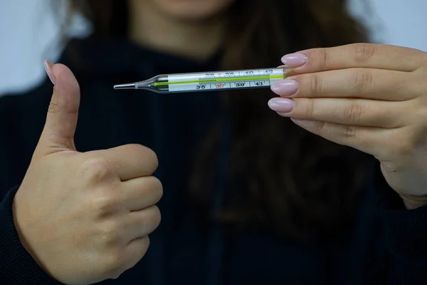 Young woman holds mercury thermometer which shows 36,6 degrees, shows like sign — Stock Photo, Image