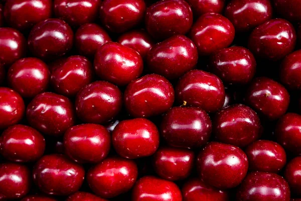 Сочные цветные фрукты на прилавках фермерского рынка на фоне красной вишни — стоковое фото