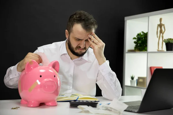 Empresario desesperado buscando billetes con una alcancía rota en primer plano — Foto de Stock