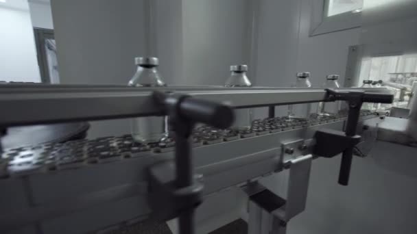 Szklane butelki wypełnione gumowymi i aluminiowymi kapslami na linii przenośnika roztworu medycznego — Wideo stockowe
