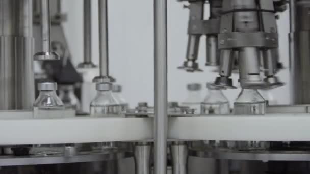 Glazen flessen gevuld en afgesloten met rubberen doppen op een medische oplossing transportband aluminium dop verpakking sectie selectieve focus — Stockvideo