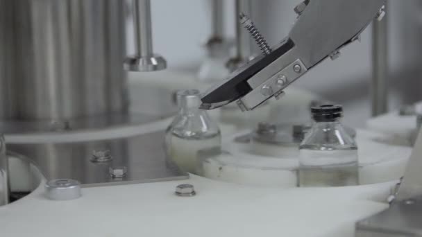 Bottiglie di vetro riempite e sigillate con tappi di gomma su una linea di trasportatori per soluzioni mediche sezione di confezionamento tappi in alluminio — Video Stock