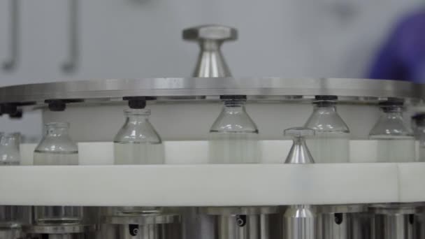 Szklane butelki wypełnione gumowymi nakrętkami na linii przenośnika roztworu medycznego — Wideo stockowe