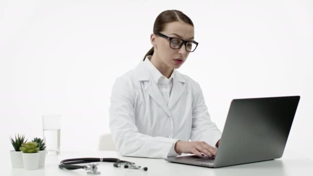 Femme médecin caucasien en manteau médical blanc, lunettes travaille au bureau à l'ordinateur portable — Video