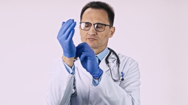 Middle aged experienced proctologist puts sterile medical gloves in hands. — Stock Video