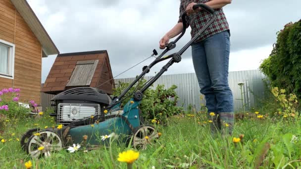 Mujer rubia tratando de arrancar el motor de una cortadora de césped, el trabajo de verano en el jardín, el corte de hierba verde — Vídeos de Stock