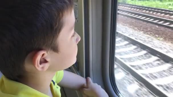 Un adolescente mirando por la ventana y viendo paisajes mientras monta en tren en movimiento — Vídeo de stock