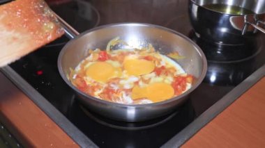 Aşçı omlet pişiriyor, tavada yumurta çırpıyor domates ve soğanla, evde sebzeli omlet pişiriyor.