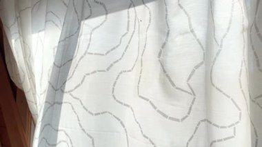 Açık şeffaf bir perde. Güneşli bir yaz gününde, kırsal kesimde rüzgarla hafifçe hareket ediyor.