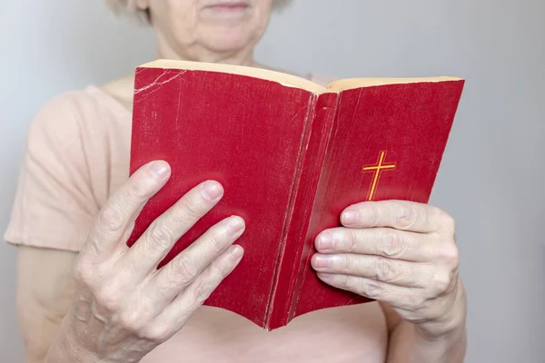 Mujer mayor sosteniendo una vieja y santa Biblia en las manos, anciana sosteniendo el Nuevo Testamento y orando — Foto de Stock