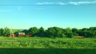 Hareket eden bir trenin penceresinden manzara yeşil manzaralı, tarlalı, tepeli ve köylü