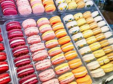 Bir sürü badem kurabiyesi, sarı, turuncu ve kırmızı renkli kurabiyeler bir şeker dükkanında satılıyor.