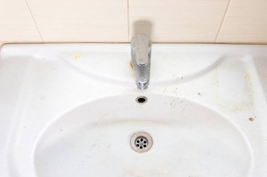 Pas lekeleri, kireç boyası ve banyoda musluğu olan eski kirli lavabo, su musluğu.