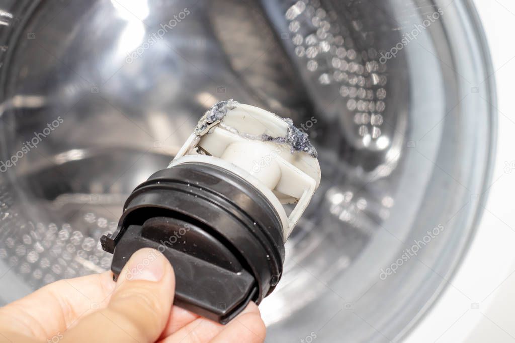 Inspecting washing machine's dirty clogged drain pump filter close up, clean and repair