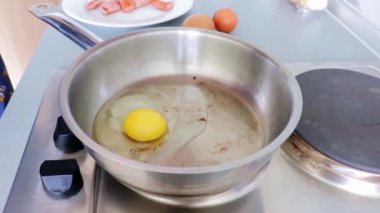 Çelik tavada kızarmış yumurta pişiren kadın.