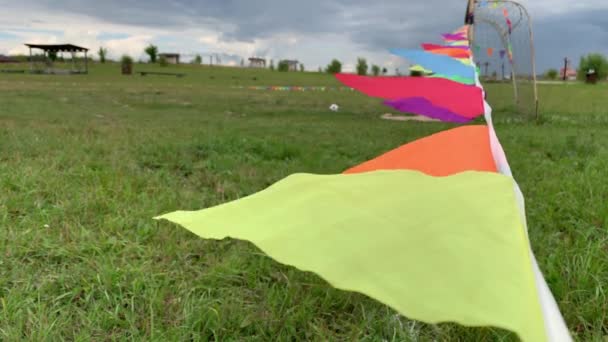 Färgglada triangeln flaggor på strängen vinka i vinden på en fotbollsplan under sport festival — Stockvideo