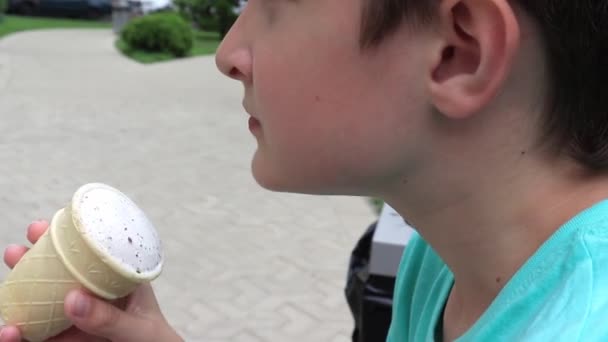 Um retrato de um menino pré-adolescente comendo gelado ao ar livre no dia de verão — Vídeo de Stock