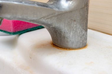Kireç pullu kirli musluk, kireç skalalı kireç suyu musluğu ve banyodaki lavabonun üzerindeki sünger, kapat, ev temizliği konsepti.
