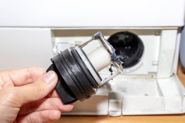 Çamaşır makinesinin kirli tıkanmış drenaj pompasını inceliyorum. Kapat, temizle ve onar.