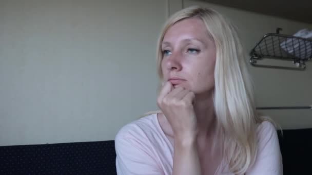 Junge blonde Frau, die mit dem Zug reist, vorsichtige Frau, die im Zug sitzt, träumt und entspannt — Stockvideo