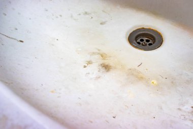 Üzerinde kireç veya kireç pulu ve pas olan bir lavabo boşaltma deliği, sabun lekeli paslı banyo lavabosu.