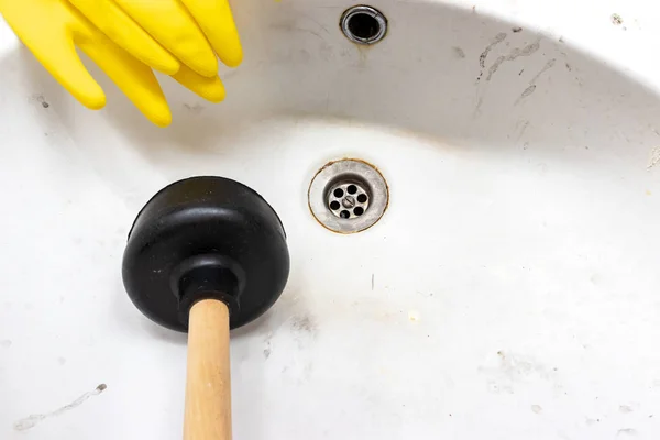 Blockerad avlopp, igensatt tvättskål, tvättställ, gula gummihandskar och en pistong nära badrummet hemma — Stockfoto