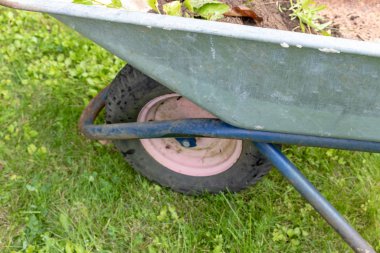 El arabasının ön tekerleği bahçenin çimlerinde duruyor, bahçecilik ve bahçıvanlık konsepti...