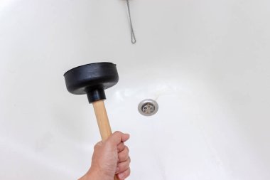 Küvet giderini temizlemek için pompa tutan kadın, kanalizasyon tıkanmış, saçları dökülmüş.