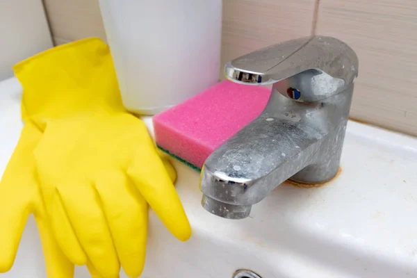 Продукти для чищення, рукавички та губка для миття брудного крана з вапняним розмахом, вапняний водяний кран з вапняним набором на раковині у ванній — стокове фото