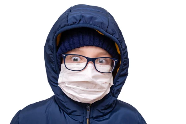 Conceito de quarentena do coronavírus. Um menino de roupas de inverno e uma máscara cirúrgica médica respiratória branca como proteção contra vírus e bactérias — Fotografia de Stock