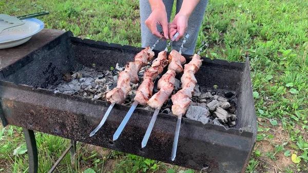 A person cooking meat kebab preparing on a barbecue grill fire in garden, backyard, the smoke and heat there — Stock Photo, Image