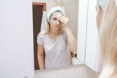 Kadın için sabah ve akşam rutini, yüzünü pamuklu ped ve yüz losyonuyla temizliyor. Toprak, makyaj, yüz bakımı konsepti.