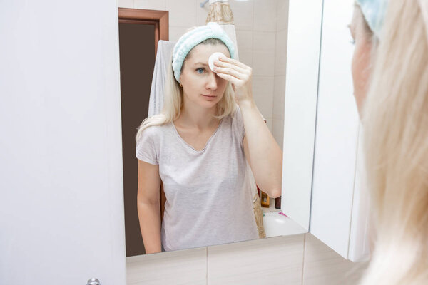 Morning and evening routine for woman, she cleansing her face with a cotton pad and face lotion to remove dirt and make-up, facial care concept