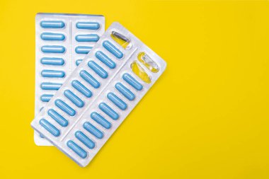 İki paket antibiyotik, zatürreeye karşı antiviral hap ve sarı zemin üzerinde fotokopi alanı olan bakteriyel enfeksiyon.