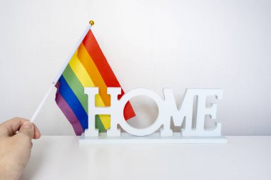 Igbt gökkuşağı gay gurur bayrağı ve beyaz arka planda bir tabela tutan bir el.