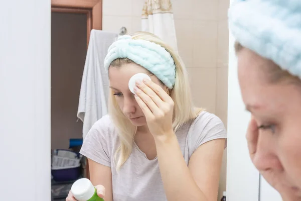 Mujer limpiando su cara con una almohadilla de algodón y gel micelar para eliminar la suciedad y el maquillaje de la cara — Foto de Stock