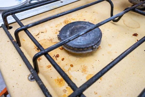 Dirty unhygienic surface of kitchen gas stove with grease and soot stains, close up