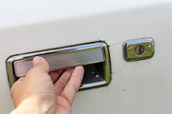 Hand holding a car door handle, trying to open the door of an old car, theft and robbery prevention concept — 스톡 사진