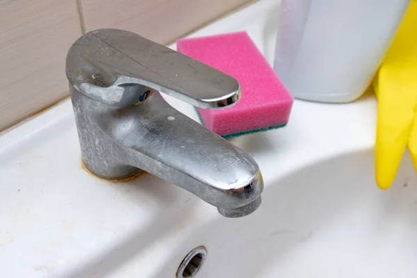 Productos de limpieza, agentes guantes y esponja para lavar el grifo sucio con cal, grifo de agua calcificada con escala de cal en el lavabo en el baño — Foto de Stock