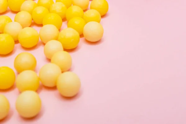 Dragoni gialli rotondi di vitamina c, acido ascorbico vicino a una bottiglia di plastica bianca, contenitore su sfondo rosa — Foto Stock