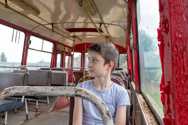 10-летний мальчик, едущий в старом винтажном автобусе, он грустит, потому что его бедная жизнь и автобус движутся по грязной сельской дороге — стоковое фото