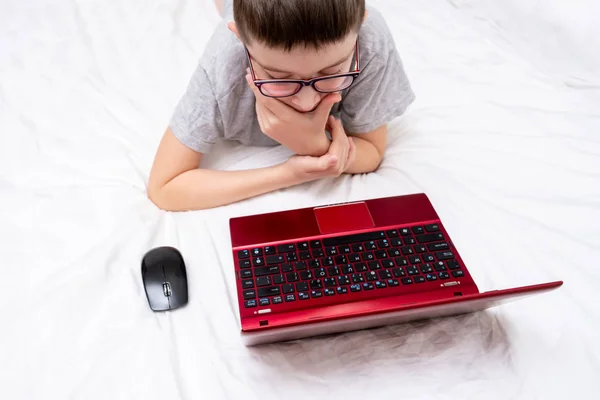 Niño Con Gafas Acostado Cama Usando Una Computadora Portátil Escribiendo —  Fotos de Stock