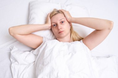 Güzel hasta bir kadın baş ağrısı, migreni ve ıstırabı ile yatakta yatıyor..