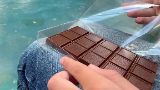 Manos de un niño rompiendo, compartiendo una barra de chocolate con leche en pedazos de cerca — Vídeos de Stock