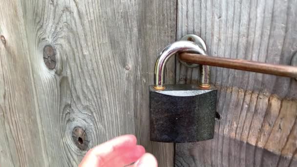 Une main touchant grand cadenas verrouillé en métal sur une porte fermée en bois close up, concept de protection de propriété privée — Video