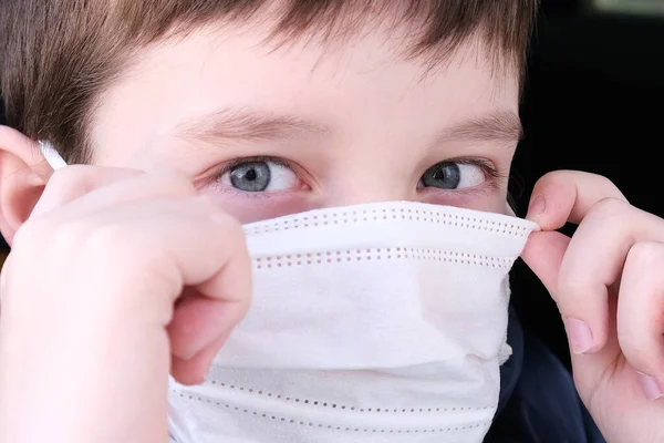 車の中で10代の男の子は ウイルス病 コロナウイルスの予防に対する保護として白い保護外科的医療面マスクを置くクローズアップ — ストック写真